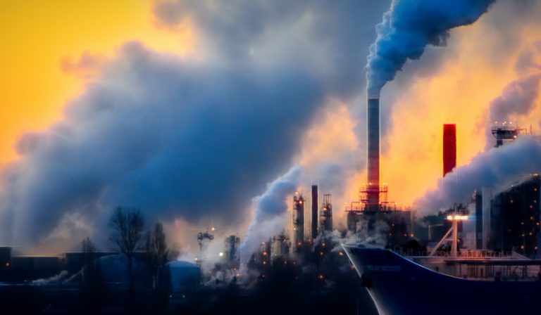 A boat in front of a factory emitting smoke