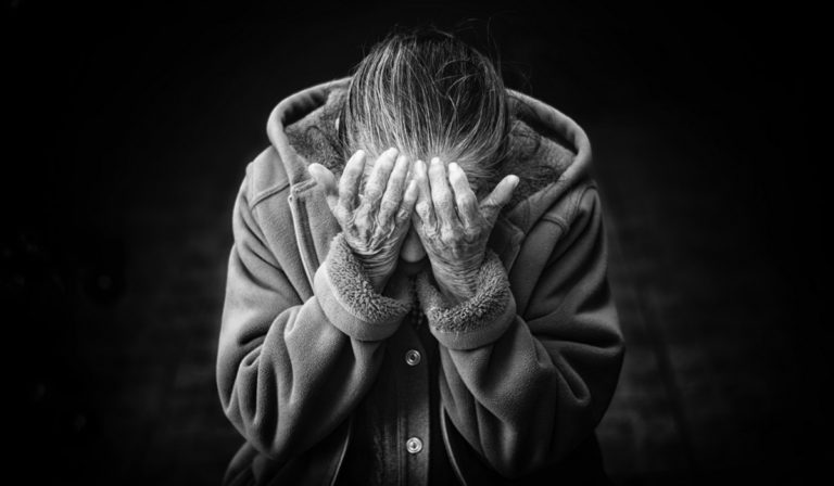 Elderly woman with head in hands