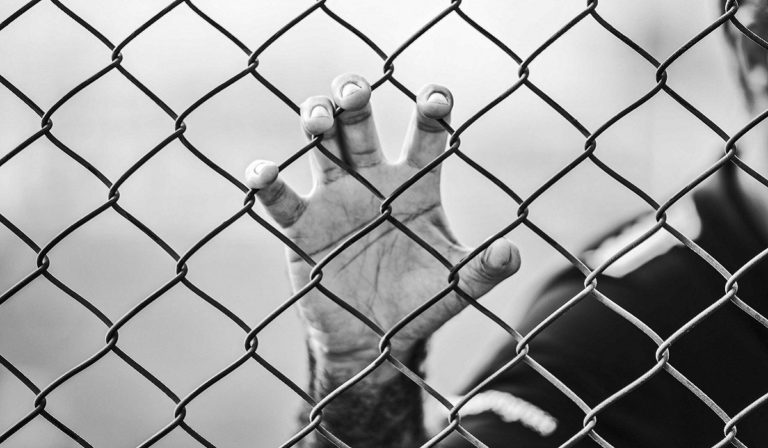 Hand holding on to chain link fence