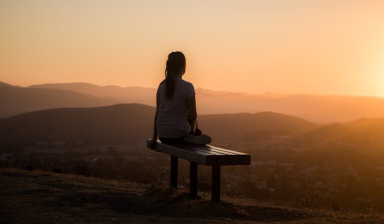 Person sitting on a bench overlooking sunset