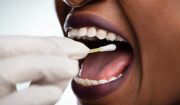 Dentist's Hand Taking Saliva Test From Woman's Mouth