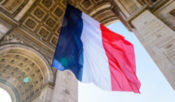 A large french flag fluttering under the Arc de Triomphe in Paris