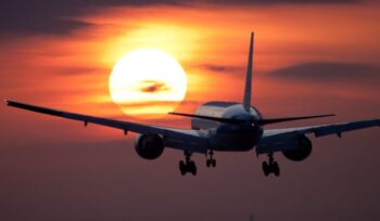 Airplane taking off against sunset