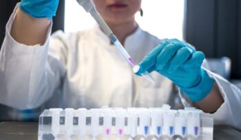 Female scientist pipetting colored chemicals into a tube