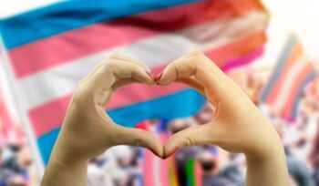 Hands making hear shape over transgender flag in background