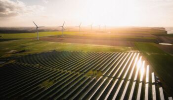 Solar farm with wind turbines in background