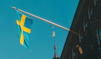 Swedish flag hanging from a building|raphael andres unsplash